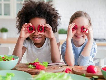 Kinder mit Gemüse für einen veganen Salat.